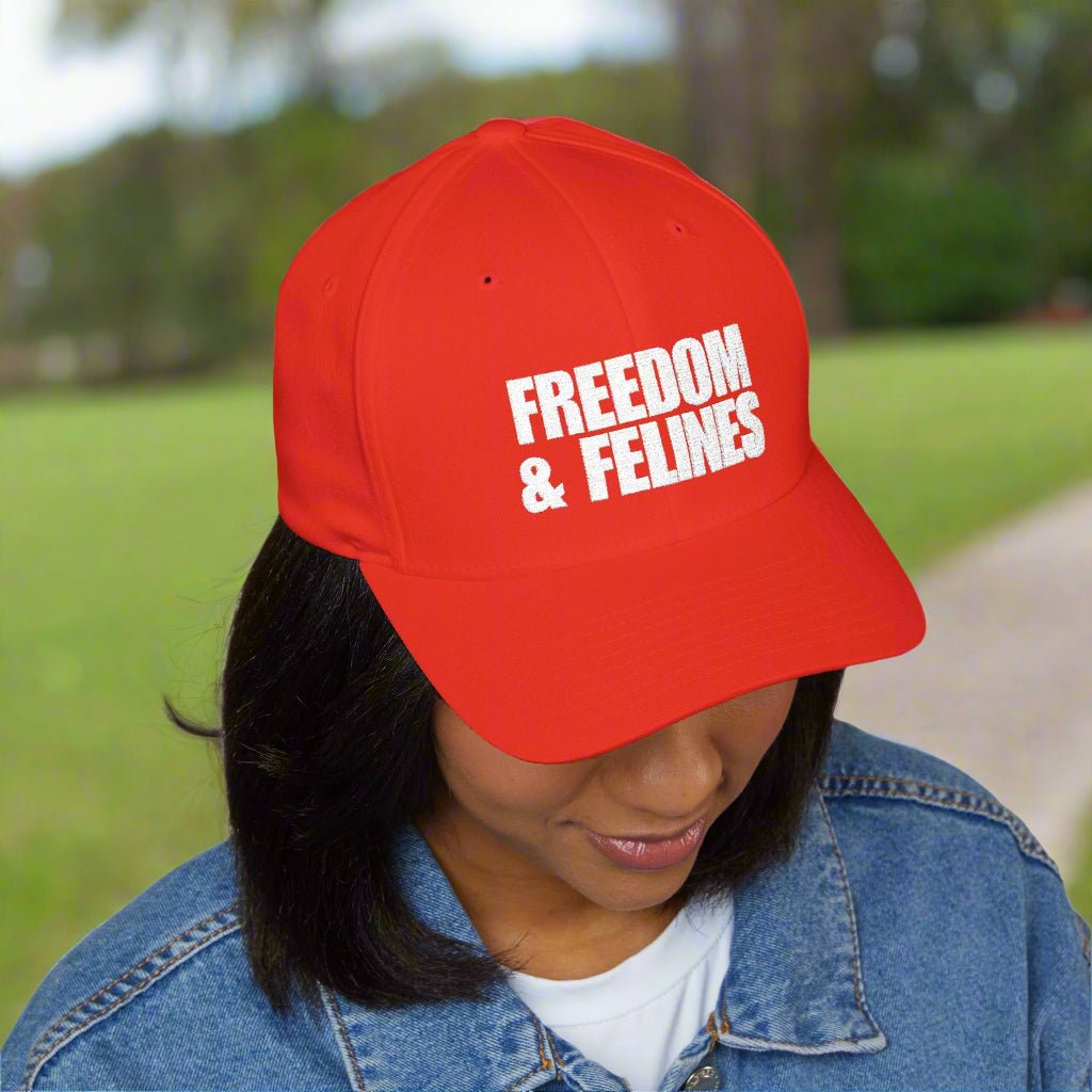 Woman wearing a red baseball cap/trucker's hat that reads, in white writing, "Freedom & Felines."