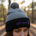 Still Here Pom-Pom Beanie – Epilepsy Awareness Knit Hat with Purple Ribbon - Hats, Beanie - EpiAl's Shop